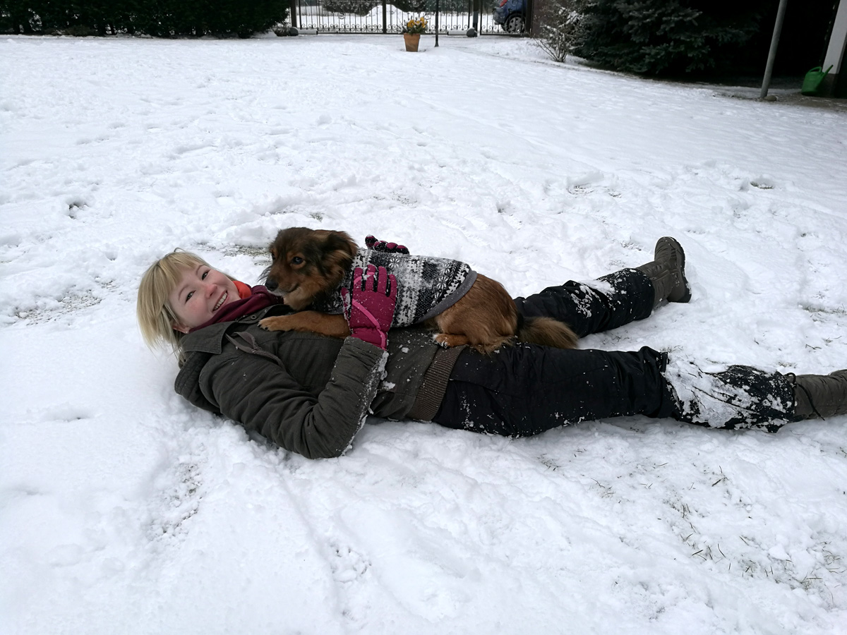 brauner-hund-liegt-auf-frau-im-schnee Liebe Grüße vom Waldi