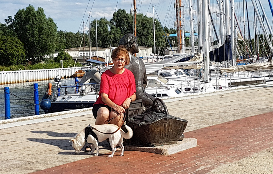 Hund-cara-mit-frau-an-einer-statue Urlaubsgrüße von Cara